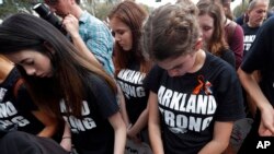 Student survivors from Marjory Stoneman Douglas High School bow their heads as the names of shooting victims are read, at a rally for gun-control reform on the steps of the state Capitol in Tallahassee, Fla., Feb. 21, 2018.