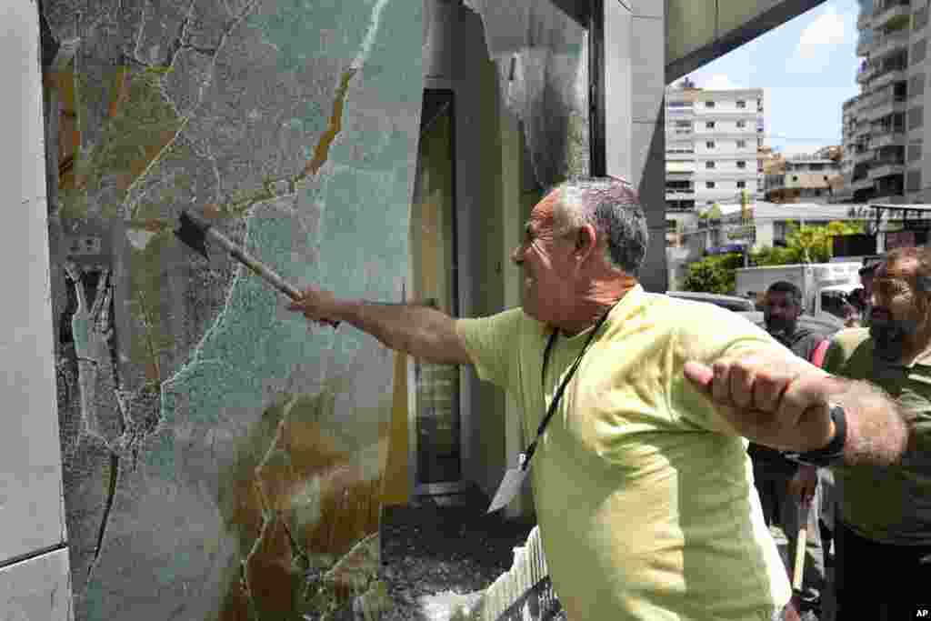 Seorang nasabah yang marah memecahkan jendela di cabang Bank Byblos selama aksi protes menuntut pencairan dana tabungan para deposan, di Beirut, Lebanon, Kamis, 15 Juni 2023. (AP)&nbsp;