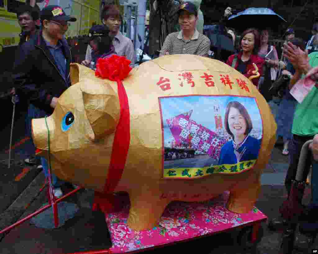 民进党支持者围绕一个大猪捐钱罐，有人手持百元钞票，要放进去