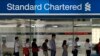 People queue up outside a Standard Chartered Bank branch before operation hours at the central business district in Singapore January 23, 2014. Standard Chartered's Chief Executive Peter Sands said takeover talk that has resurfaced around his bank after r