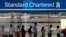 People queue up outside a Standard Chartered Bank branch before operation hours at the central business district in Singapore January 23, 2014. Standard Chartered's Chief Executive Peter Sands said takeover talk that has resurfaced around his bank after r