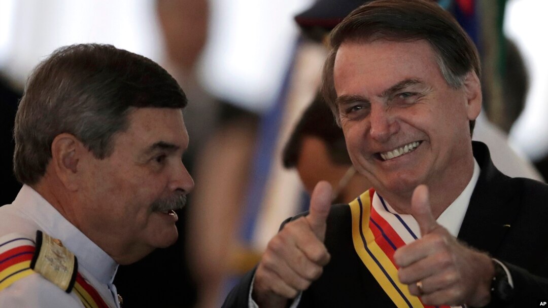 Brazil's President Jair Bolsonaro flashes two thumbs up standing next to Adm. Marcus Vinicius Oliveira dos Santos, Supreme Military Court president, who presented Bolsonaro with the Order of Military Judicial Merit, in Brasilia, Brazil, March 28, 2019.