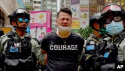 Polisi menahan seorang pedemo setelah disemprot semprotan merica dalam unjuk rasa di Causeway Bay, Hong Kong, 1 Juli 2020.