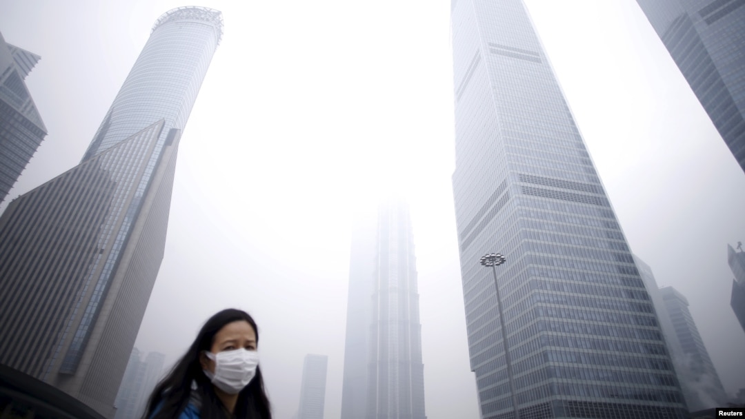 A woman wearing a mask walks past below skyscrapers amid heavy smog at the financial district of Pudong, in Shanghai, China, Dec. 11, 2015. 