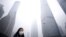 A woman wearing a mask walks past below skyscrapers amid heavy smog at the financial district of Pudong, in Shanghai, China, Dec. 11, 2015. 