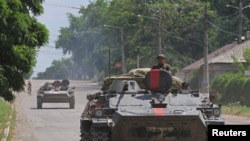 亲俄武装成员乘步兵战车行驶在被俄军攻占的乌克兰卢甘斯克州利西昌斯克的街头。(2022年7月4日)