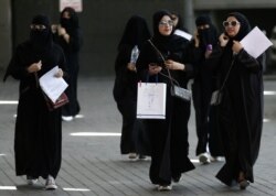 FILE - Female Saudi students walk at a job seekers fair in Riyadh, Saudi Arabia, Oct. 2, 2018.