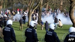 Belgian police officers surround people at the Bois de la Cambre park, in Brussels, on April 1, 2021, during an unauthorized rally for a fake concert announced on social media as an April Fool's Day prank. 