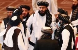 FILE - Taliban delegates speak during talks between the Afghan government and Taliban insurgents in Doha, Qatar, Sept. 12, 2020.