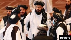 FILE - Taliban delegates speak during talks between the Afghan government and Taliban insurgents in Doha, Qatar, Sept. 12, 2020.