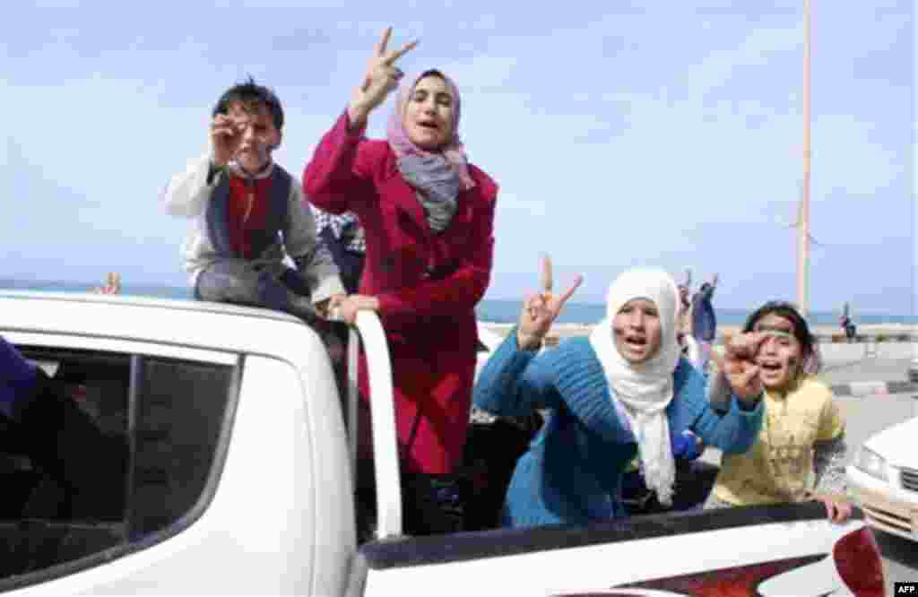 Residents riding in the back of a vehicle celebrate and display the victory sign in Benghazi, Libya on Monday, Feb. 21, 2011. Libyan protesters celebrated in the streets of Benghazi on Monday, claiming control of the country's second largest city after bl