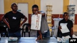 Funcionários da assembleia de voto organizam os boletins de voto antes de procederem à contagem numa assembleia de voto em Windhoek, Namíbia, em 1 de dezembro de 2024.