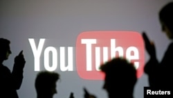 FILE - Silhouettes are seen in front of a Youtube logo, in this picture illustration taken in Zenica, Oct. 29, 2014.