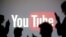 FILE - Silhouettes are seen in front of a Youtube logo, in this picture illustration taken in Zenica, Oct. 29, 2014.