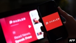 (FILES) In this file photo taken on July 01, 2020 an illustration picture shows social media application logo from Parler displayed on a smartphone with its website in the background in Arlington, Virginia. - Apple on January 9, 2021, followed…