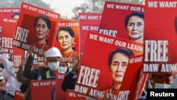 FILE - Demonstrators hold placards depicting deposed Myanmar leader Aung San Suu Kyi during a protest against the military coup, in Naypyitaw, Myanmar, Feb. 17, 2021.