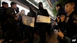 Attendees hold cards listing four of their five demands during a six months anniversary memorial for a man who fell to his death while hanging a protest banner against an extradition bill on Sunday, Dec. 15, 2019 in Hong Kong.