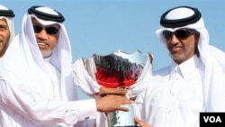 Presiden AFC Mohamed Bin Hammam, kiri, and Ketua Federasi Sepakbola Qatar Sheikh Hamad Bin Khalifa Bin Ahmed al-Thani, memegang trofi Piala Asia yang tiba di bandara internasional Doha hari Senin (3/1).