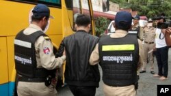 A Chinese national arrested over an alleged internet scam is escorted by police officers to be deported at the immigration office in Phnom Penh, Cambodia, July 26, 2017. 