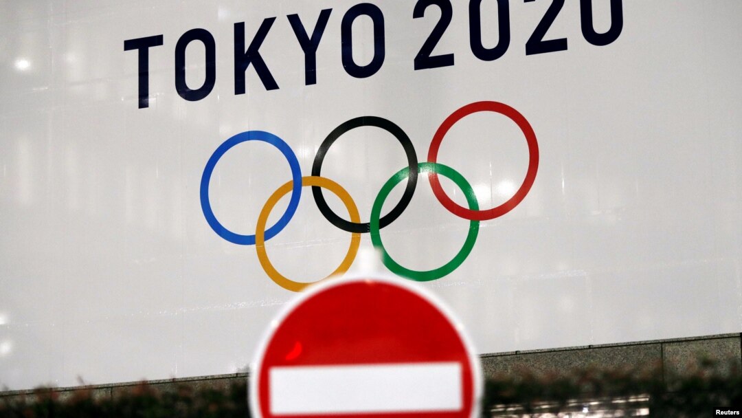 东京街头交通警示牌后的东京奥运会的标识。（2020年3月23日）