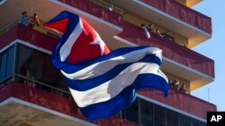 FILE - People watch a concert given by Puerto Rico's Olga Tanon, from a building flying a Cuban flag in Havana, Cuba, Saturday, Dec. 12, 2015.