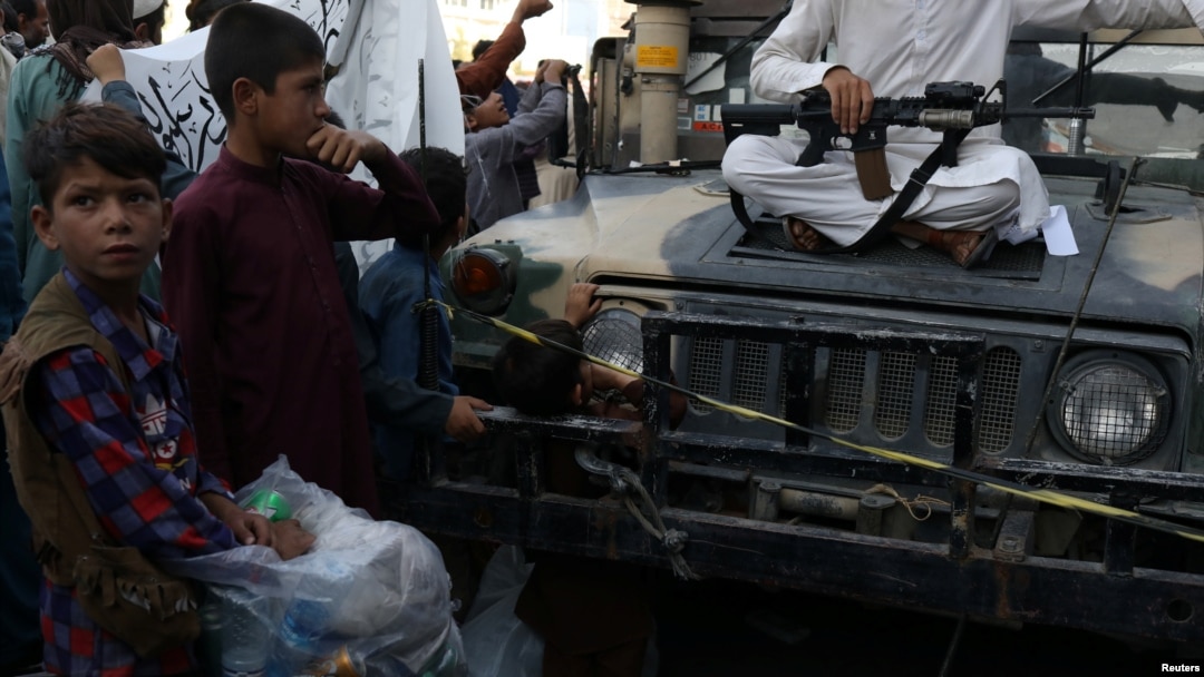 Anak-anak Afghanistan mengamati senjata seorang tentara Taliban di Kabul, Afghanistan, 1 September 2021. WANA (West Asia News Agency) via REUTERS