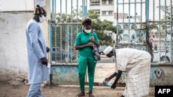 Une lycéenne du lycée Blaise Diagne se fait désinfecter les pieds le premier jour de son retour à l'école à Dakar le 25 juin 2020, après la fermeture des écoles début mars 2020 en raison de la pandémie de COVID-19 au Sénégal. (AFP/JOHN WESSELS)