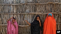 FILE - Somali refugee girls stand by the fence surrounding their hut at Dadaab refugee camp in northern Kenya Tuesday, Dec. 19, 2017.