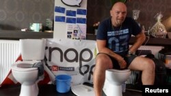 Jimmy de Frenne, warga Belgia, duduk di toilet sebuah kafe untuk memecahkan rekor baru duduk di toilet terlama Guinness Book of Records, di Ostend, Belgia, 11 Juli 2019. (Foto: Reuters)
