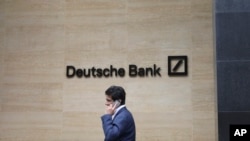 A man walks past the Deutsche Bank sign in London, July, 8, 2019. 