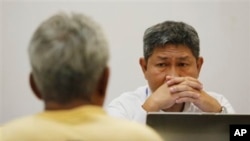 ထိုင်းလူမှောင်ခိုကုန်ကူးသူ Samruay Chatkrod (ဝဲ) ကို ထိုင်းအထူးစုံစမ်းစစ်ဆေးရေးမှူးတယောက်က စစ်ဆေးနေစဉ်။ (ဇူလိုင် ၁၊ ၂၀၁၅) 