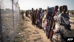 FILE - Women wait in a line for a food distribution by the United Nations World Food Program (WFP) in Gumuruk, South Sudan, June 10, 2021.