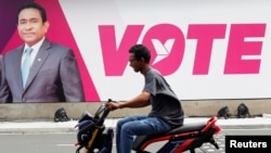 A man rides a motorcycle past an image of Maldives President Abdulla Yameen on a road ahead of the presidential election in Male, Maldives, Sept. 19, 2018.