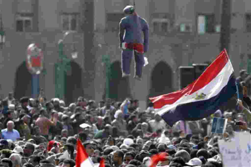 Egyptian protesters wave Egyptian flags under an effigy representing a hanged President Mubarak during a protest in Tahrir square in Cairo, Egypt, Friday, Feb.4, 2011. The Egyptian military guarded thousands of protesters pouring into Cairo's main square