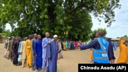 FILE- People wait to receive food donations from the United Nations World Food Program in Damasak, northeastern Nigeria, Oct. 6, 2024.