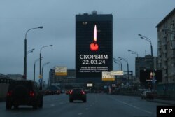 FILE—Cars drive past an advertising screen on the facade of a building displaying an image of a lit candle and the slogan "(We) Mourn 22.03.24" in Moscow on March 23, 2024.