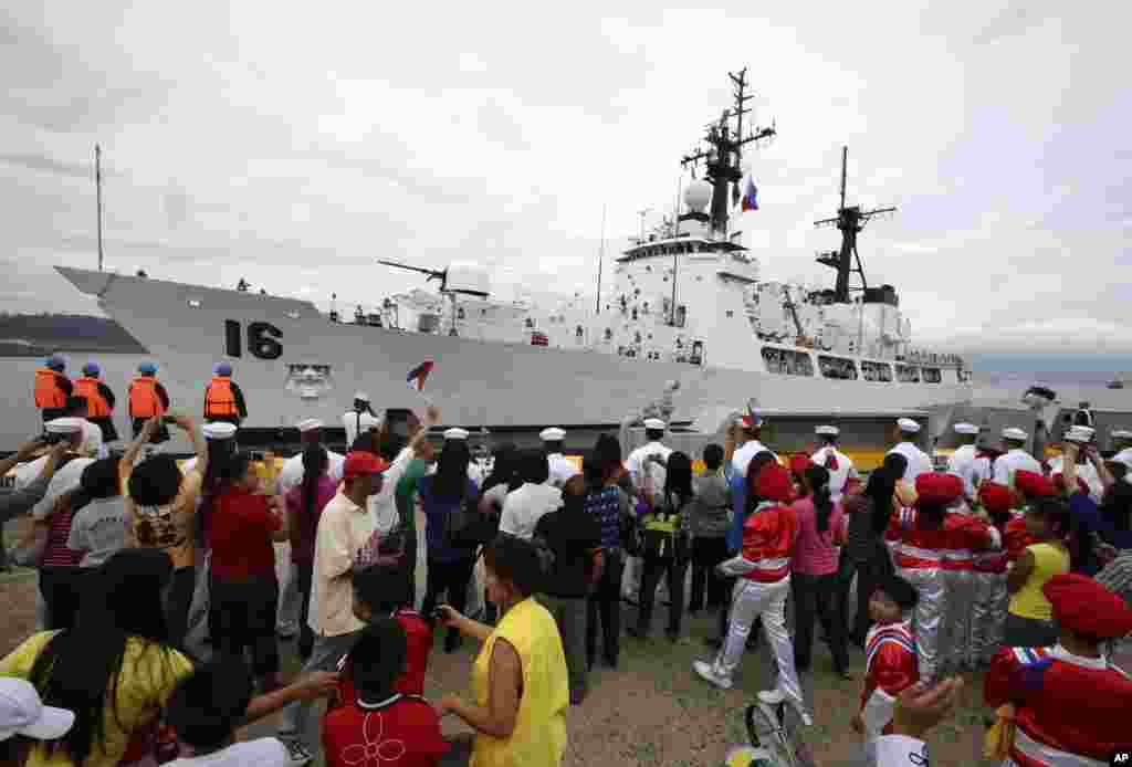 Students and other guests wave Philippine flags to welcome the BRP Ramon Alcaraz at Subic Freeport, August 6, 2013. 