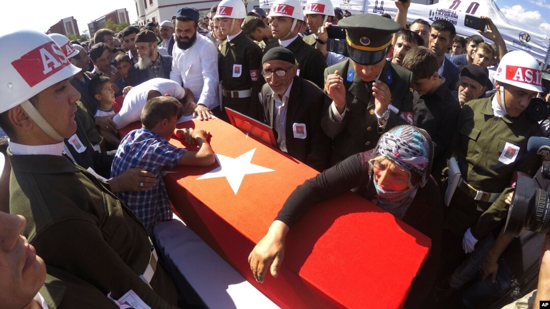 Fehime Aydemir (R), the mother of Turkish officer Metin Aydemir, cries over his flag-draped coffin during funeral services in his hometown of Erzurum, eastern Turkey, Aug. 19, 2015. Aydemir was one of the three officers killed Tuesday in an operation agai