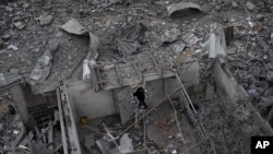 A Palestinian man walks among debris after an Israeli airstrike at Hamas Prime Minister Ismail Haniyeh's office in Gaza City, Saturday, Nov. 17, 2012. 