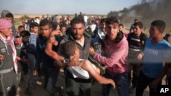 Palestinian protesters carry a wounded man who was shot by Israeli troops during a protest near the Gaza Strip border with Israel, in eastern Gaza City, March 31, 2018. 