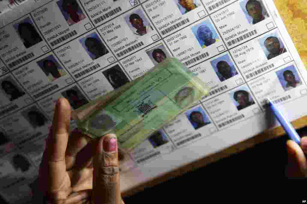 An election official verifies the particulars of a person on the electoral roll during presidential election day in Lusaka, Tuesday, Jan. 20, 2015. 