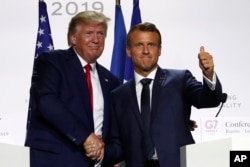 FILE - U.S. President Donald Trump and French President Emmanuel Macron shake hands at the G-7 summit on Aug. 26, 2019, in Biarritz, France.