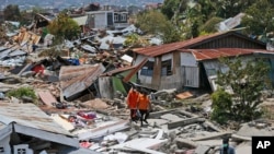 Rescuers carry a body bag containing the remains of an earthquake victim through a neighborhood flattened by Friday's earthquake in Palu, Central Sulawesi, Indonesia, Oct. 2, 2018. 