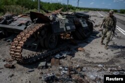 Seorang prajurit Ukraina berjalan di dekat tank Ukraina yang hancur di dekat Desa Robotyne. (Foto: Reuters)