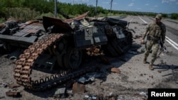 Seorang tentara Ukraina berjalan di samping tank milik pasuka Ukraina yang hancur di desa Robotyne, wilayah Zaporizhzhia, pada 25 Agustus 2023. (Foto: Reuters/Viacheslav Ratynskyi)