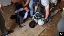 In this undated video grab provided by the RU-RTR Russian television via APTN on Aug. 14, 2017, Russian FSB officers arrest two men on suspicion of plotting a series of attacks outside Moscow. 