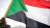 FILE - The White House is visible behind a man holding a Sudanese flag at a rally in Washington, June 8, 2019. The Sudanese government said March 26, 2021, that it had cleared all of its past-due repayments to the World Bank. 