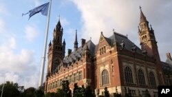 FILE - A United Nations flag flutters in the wind next to the International Court of Justice in the Hague, the Netherlands, Aug. 27, 2018. Judges at the United Nations' highest court are listening to arguments in a case focused on whether Britain illegally maintains sovereignty over the Chagos Islands in the Indian Ocean, including Diego Garcia, where the United States has a major military base.
