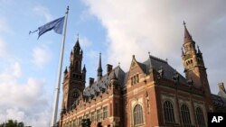 FILE - A United Nations flag flutters in the wind next to the International Court of Justice in the Hague, the Netherlands, Aug. 27, 2018.