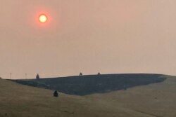 El humo oscurece el aire y el sol sobre una ladera quemada por un incendio forestal reciente, en Missoula, Montana, el domingo 18 de julio de 2021.